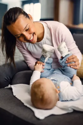 Jeune garde d'enfants / assistante maternelle heureuse jouant avec son bébé tout en passant du temps ensemble à la maison.